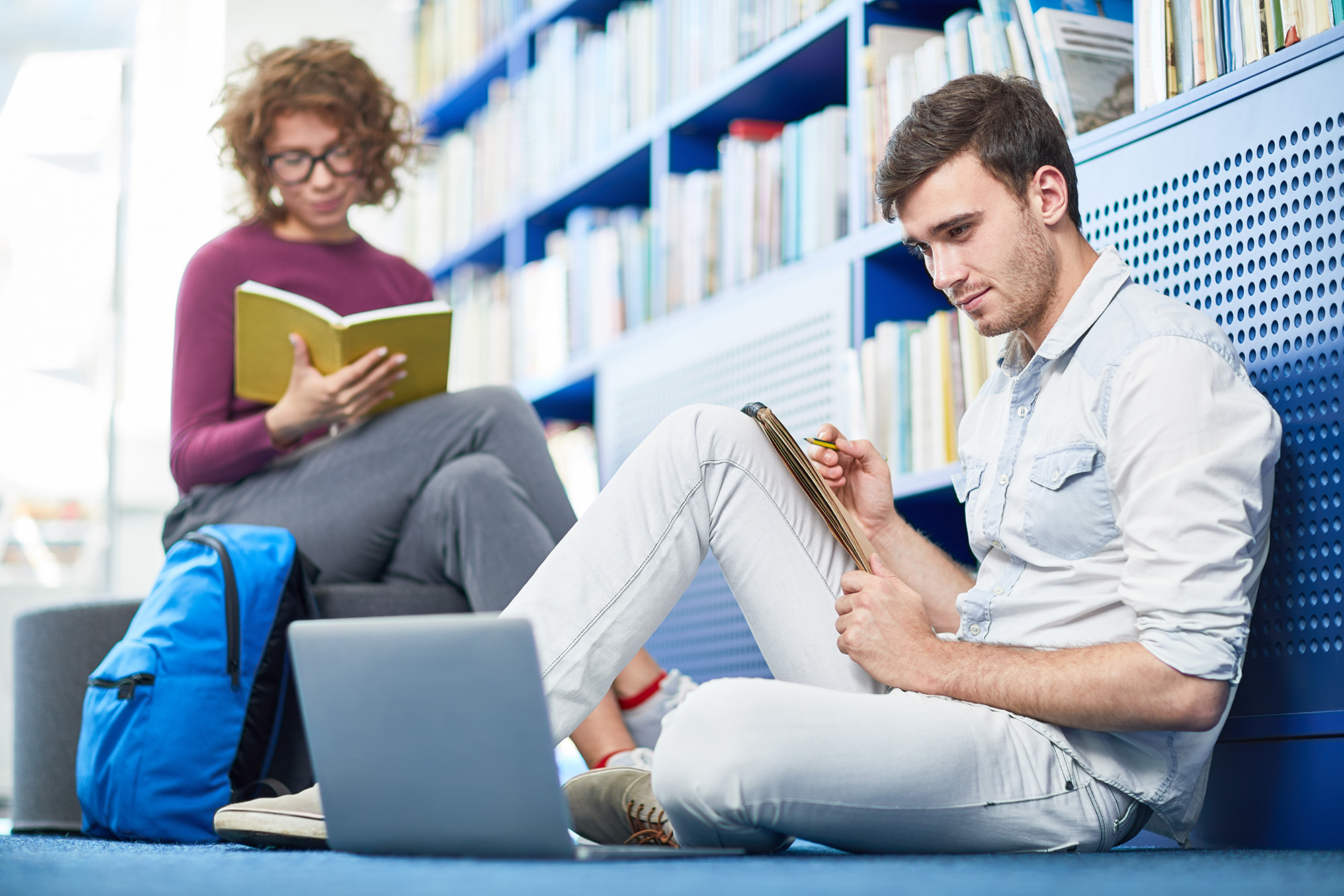 uczniowie w bibliotece siedzący na podłodze z ksiązkami